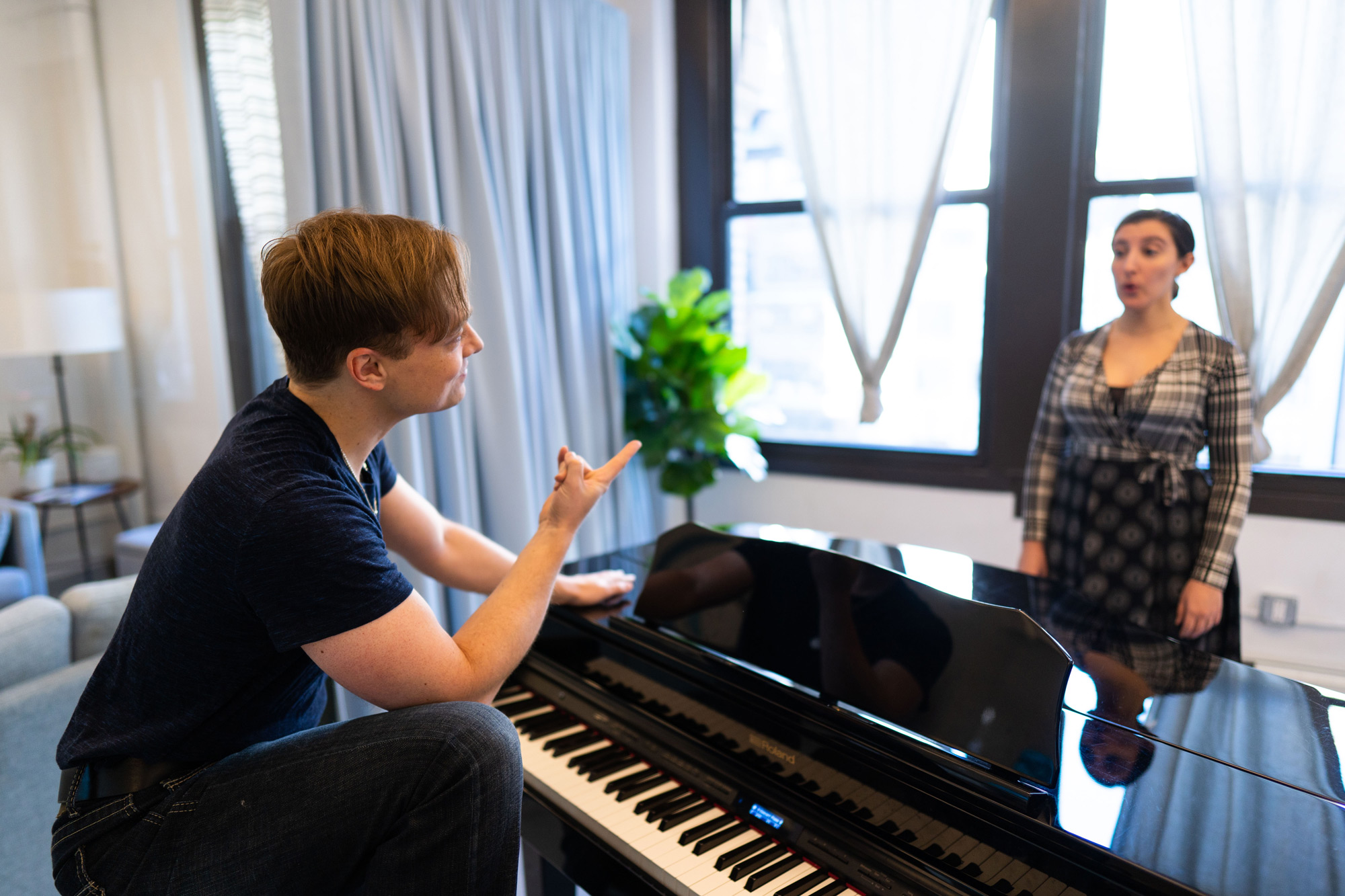 Justin teaching behind piano pointing finger